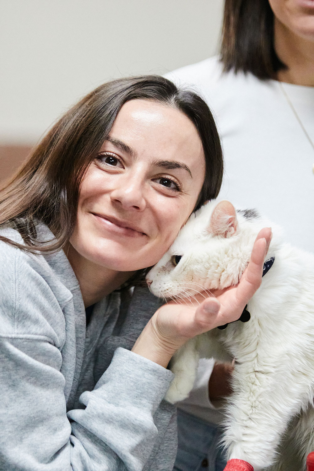 An image of a woman with a white cat next to her face.