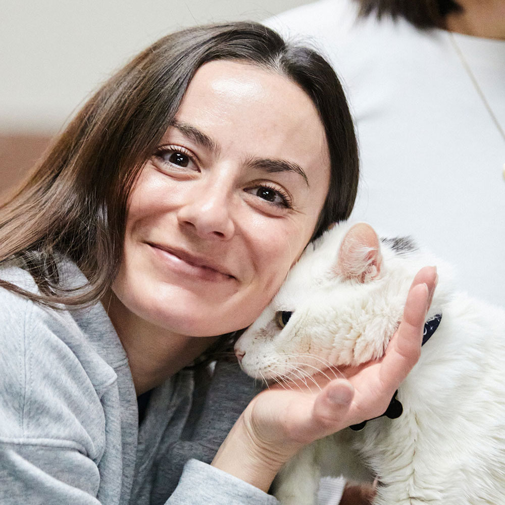 A woman holding a white cat close to her face.